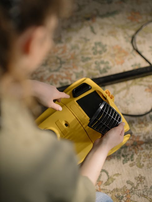 A woman using a yellow and black vacuum cleaner to perform surface cleaning on a patterned area rug in a living room. The rug features floral motifs in soft shades of beige, green, and orange, placed 